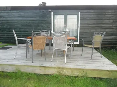 a wooden deck with a table and chairs on it at Bed & Breakfast ARKEN AE in Zuiderwoude