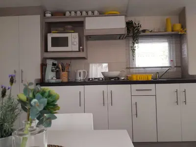 a kitchen with white cabinets and a microwave at Chalet Dalile IJmuiden aan Zee vlakbij het strand in IJmuiden