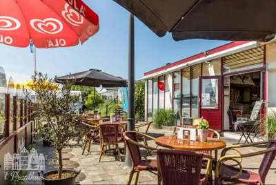 a patio with tables and chairs and an umbrella at Chalet Dalile IJmuiden aan Zee vlakbij het strand in IJmuiden