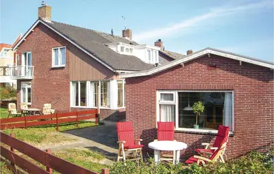 a brick house with red chairs and a table at De Vissende Beer in Egmond aan Zee