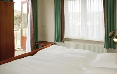 a bedroom with a white bed and a window at De Vissende Beer in Egmond aan Zee