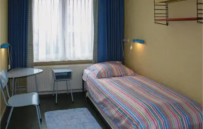 a bedroom with a bed and a table and a window at De Vissende Beer in Egmond aan Zee