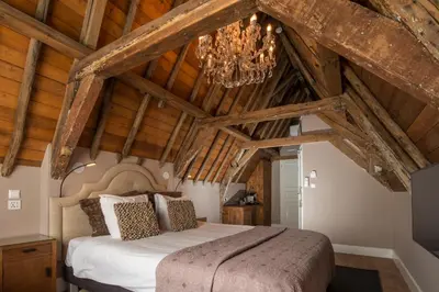 a bedroom with a large bed and a chandelier at Boutique Hotel Huys van Leyden in Leiden