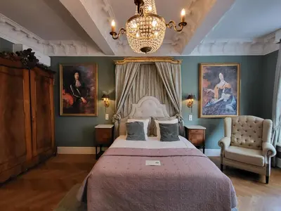 a bedroom with a bed and a chandelier and paintings at Boutique Hotel Huys van Leyden in Leiden