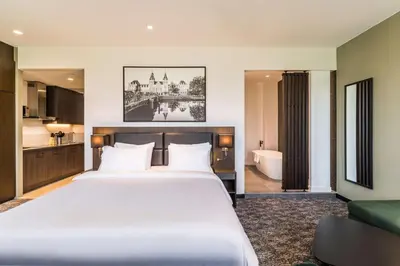 a bedroom with a large white bed and a bathroom at Radisson Hotel & Suites Amsterdam South in Amstelveen
