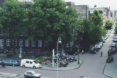 a group of people sitting at tables on a city street at Canal House Inn in Amsterdam