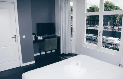 a bedroom with a bed and a desk and a window at Canal House Inn in Amsterdam