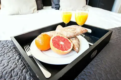 a tray with a plate of food and two glasses of orange juice at Plantage Hortus Apartments in Amsterdam