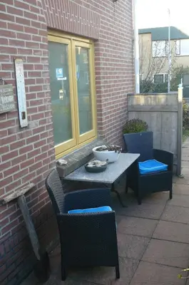 a patio with two chairs and a table with a bowl on it at Amsterdam Beach Apartment in Zandvoort