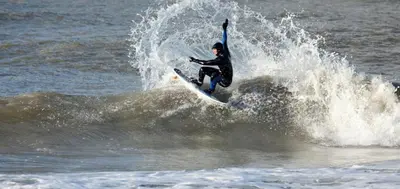 a person riding a wave on a surfboard in the ocean at Amsterdam Beach Apartment in Zandvoort