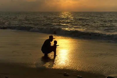 a person sitting on the beach with a child at Amsterdam Beach Apartment in Zandvoort
