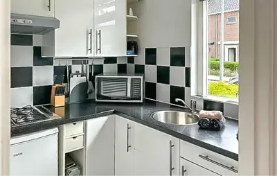 a kitchen with black and white checkered wall at Dophuisje in Egmond aan Zee