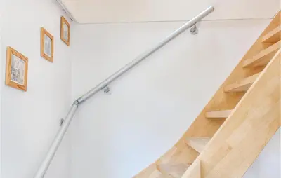 a metal stair rail in a white wall with wooden stairs at Dophuisje in Egmond aan Zee