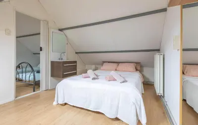 a bedroom with a bed with pink pillows on it at Dophuisje in Egmond aan Zee