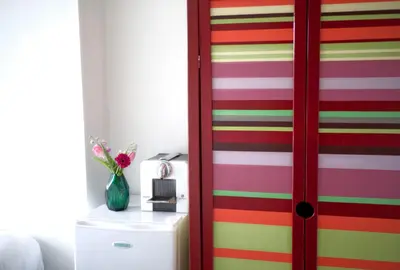 a colorful striped door in a room with a vase of flowers at Cozy Pijp Apartment Amsterdam in Amsterdam
