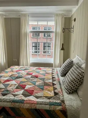 a bedroom with a quilt on a bed with a window at Dahli's Sleep Boutique in Amsterdam