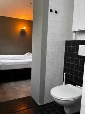 a bathroom with a toilet and a bed at Hotel Oostereiland in Hoorn
