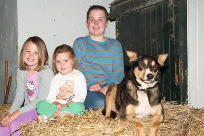 a man and two girls and a dog sitting on hay at Sint Nicolaashoeve in Nieuwveen