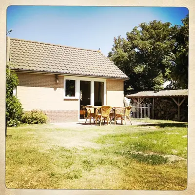 a house with a table and chairs in the yard at De Munnik in Camperduin