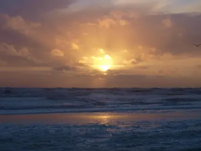 a sunset on the beach with the sun setting at De Munnik in Camperduin