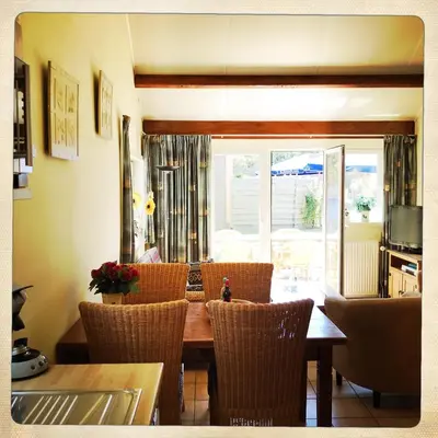 a dining room with a wooden table and chairs at De Munnik in Camperduin