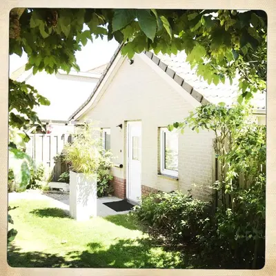 a small white house with a yard with grass at De Munnik in Camperduin
