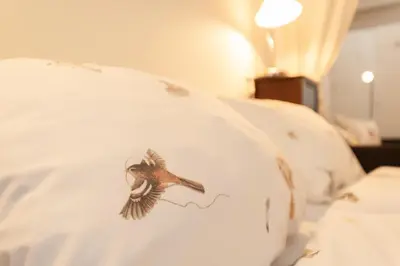 a white bed with a bird design on the pillow at CASASdeCASPER - Studio Alkmaar in Alkmaar
