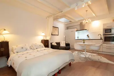 a white bedroom with a large bed and a kitchen at CASASdeCASPER - Studio Alkmaar in Alkmaar