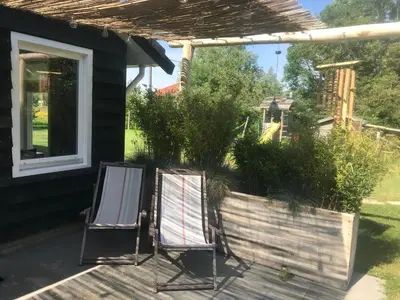two chairs sitting on a deck next to a house at de Ark in Schoorl