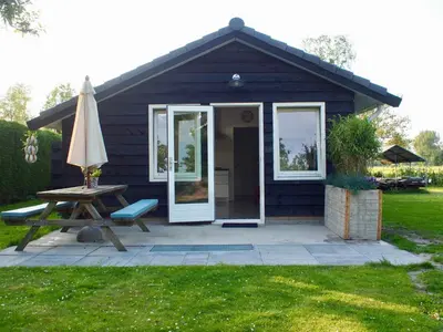 a small house with a picnic table and an umbrella at de Ark in Schoorl