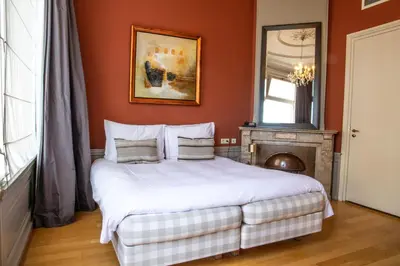 a bedroom with a large bed with orange walls at Hotel ML in Haarlem