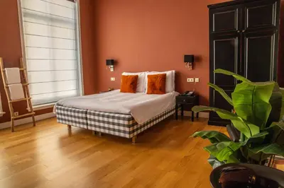 a bedroom with a bed with orange walls and wooden floors at Hotel ML in Haarlem
