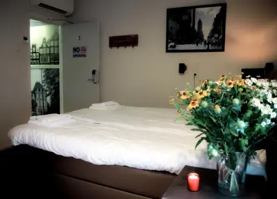 a bedroom with a bed with a vase of flowers on a table at Hotel 55 - City Centre in Amsterdam