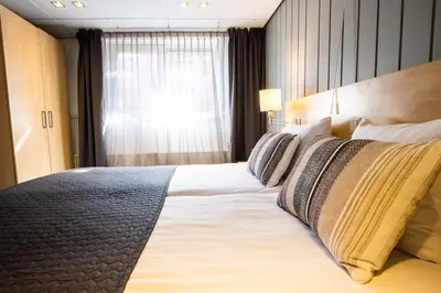 a large bed in a hotel room with a window at Hotel De Boei in Egmond aan Zee