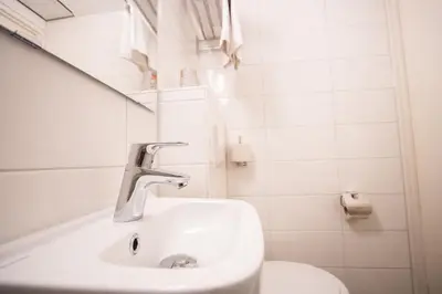 a white bathroom with a sink and a toilet at Hotel De Boei in Egmond aan Zee