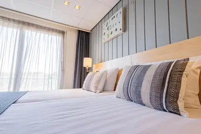 a bed in a hotel room with a large window at Hotel De Boei in Egmond aan Zee