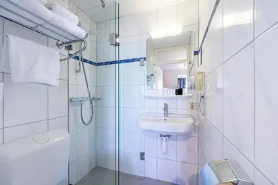 a white bathroom with a sink and a shower at Hotel De Boei in Egmond aan Zee