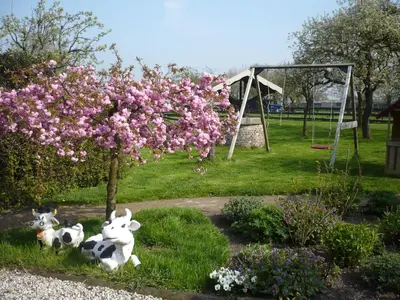 two stuffed cows sitting in the grass under a tree at Shepherds House B&B in Limmen
