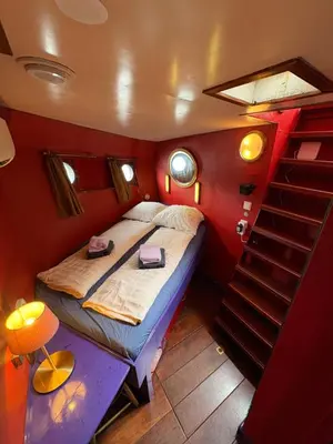 a small room with a bed and a staircase at Hotelboot Zwaan in Amsterdam