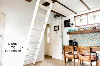a room with a ladder and a table and chairs at CASA KAREN - Houseboat studio with private terrace in Amsterdam