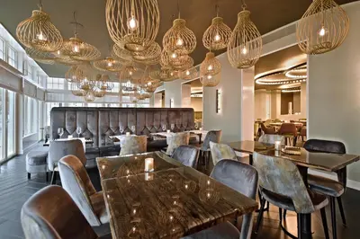 a restaurant with tables and chairs and chandeliers at Zaan Hotel Amsterdam - Zaandam in Zaandam