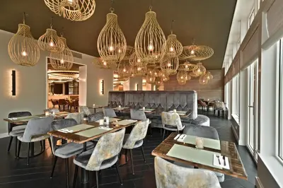a restaurant with tables and chairs and chandeliers at Zaan Hotel Amsterdam - Zaandam in Zaandam
