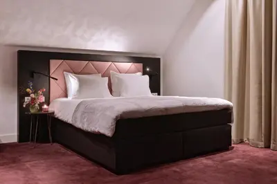 a bedroom with a large bed with a pink headboard at Zaan Hotel Amsterdam - Zaandam in Zaandam