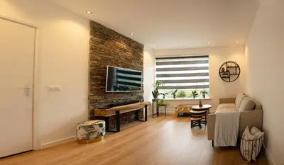 a living room with a couch and a television on a brick wall at Beautiful family house 5 min away from Amsterdam in Badhoevedorp
