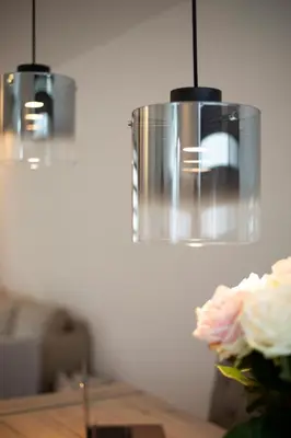 a vase with a flower on a table with two lights at Beautiful family house 5 min away from Amsterdam in Badhoevedorp