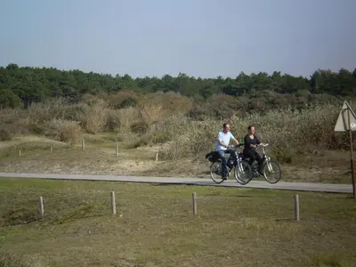 two people riding bikes on a road at Noordwijk Holiday Rentals in Noordwijk