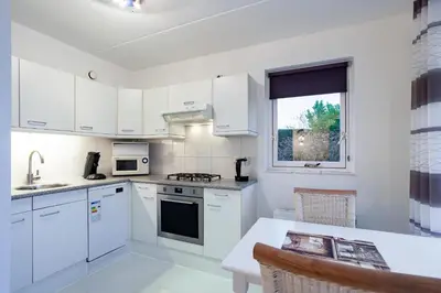 a kitchen with white cabinets and a table and a window at Noordwijk Holiday Rentals in Noordwijk