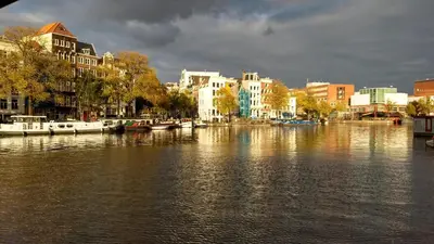 a river with boats in a city with buildings at Rembrandt Square Boat in Amsterdam