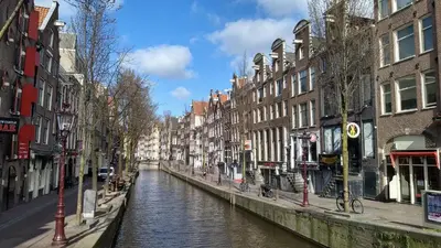 a canal in a city with buildings next to a street at Rembrandt Square Boat in Amsterdam