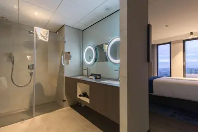 a bathroom with a shower and a bed and a sink at Postillion Hotel Amsterdam in Amsterdam
